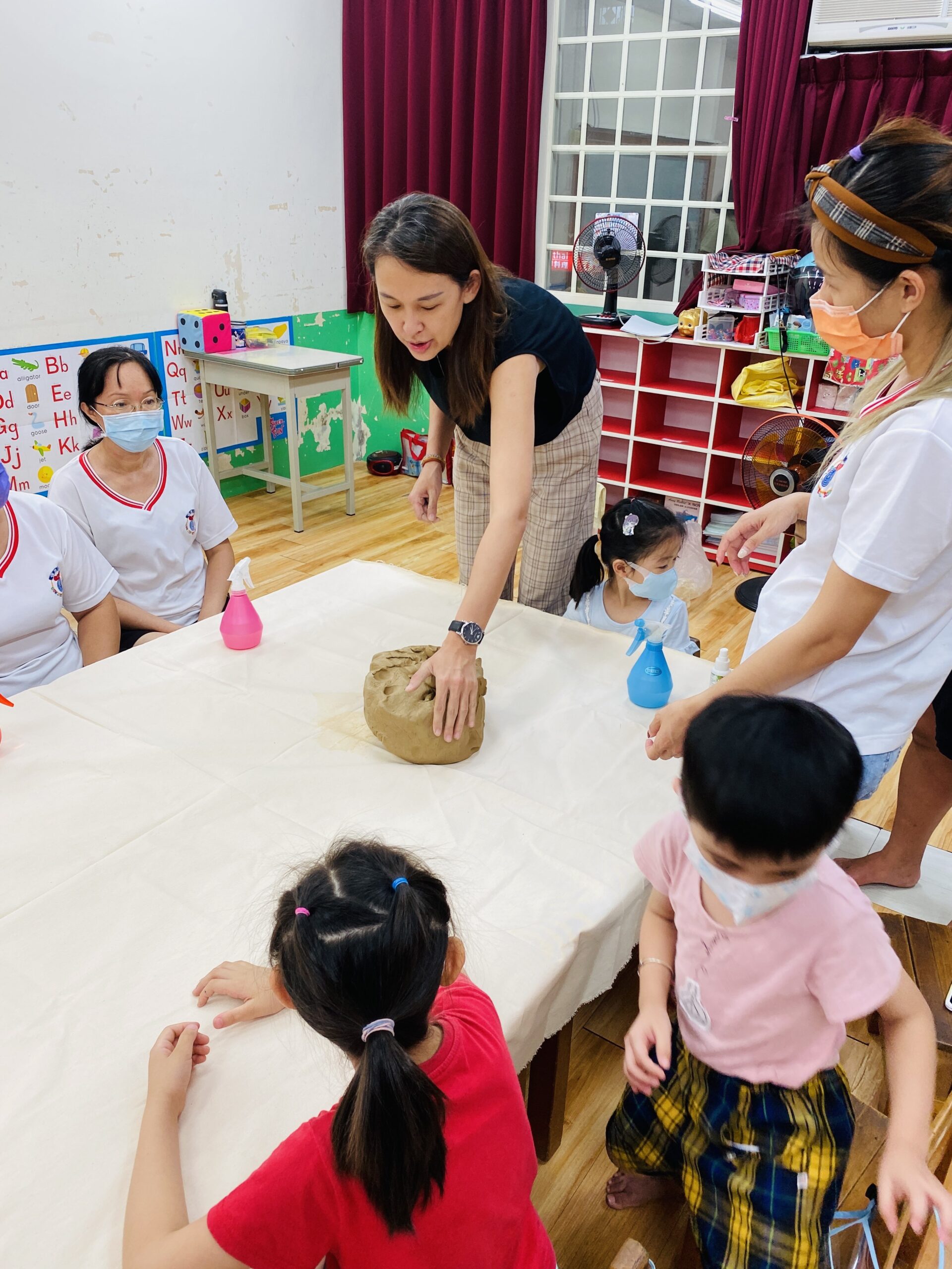 老師在教室桌邊示範黏土操作
